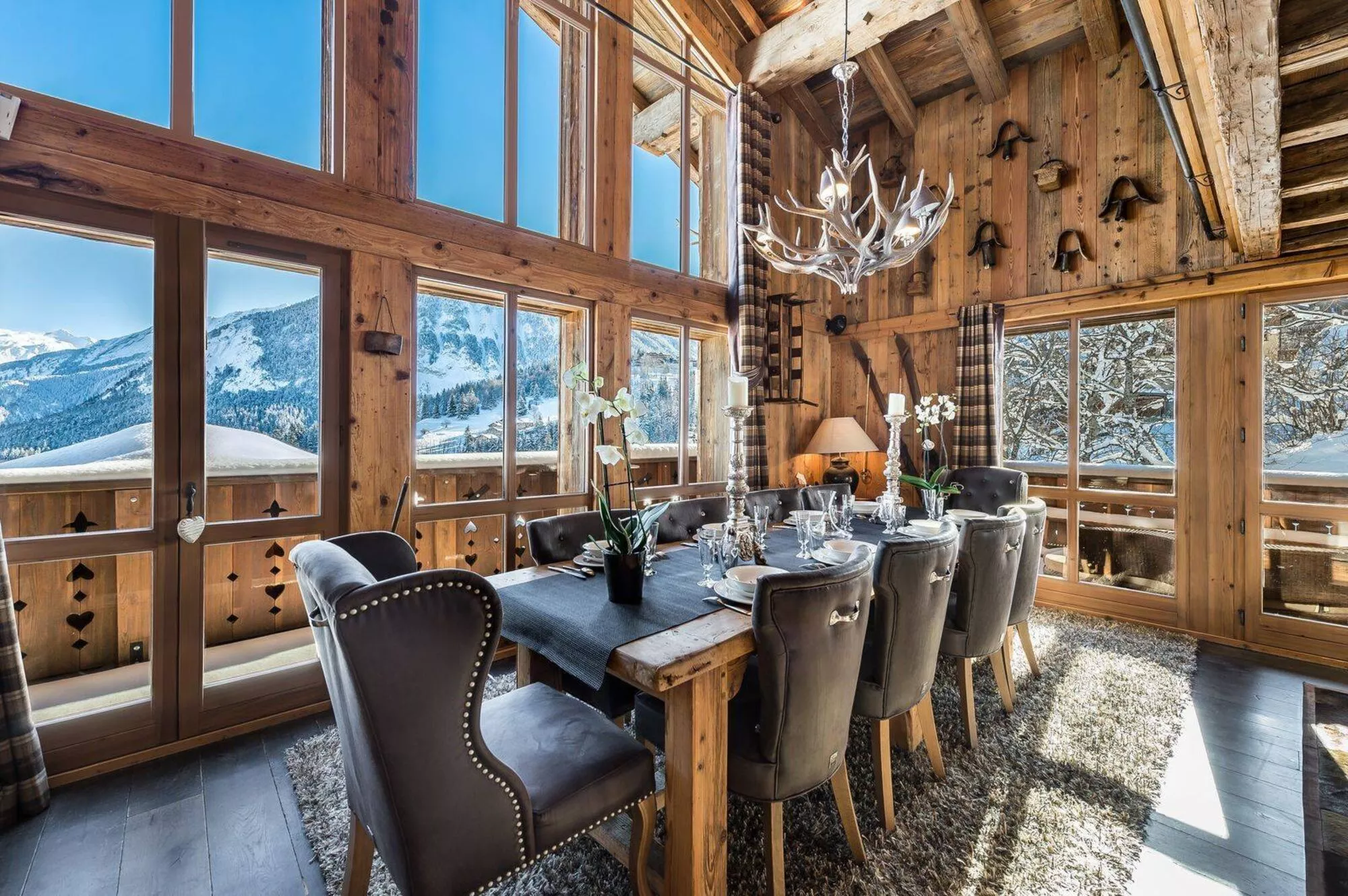Sala de jantar de chalé com lustre de galhos e vista para as montanhas