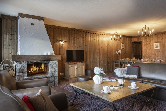 Sala de estar de chalé com lareira acesa e decoração em madeira