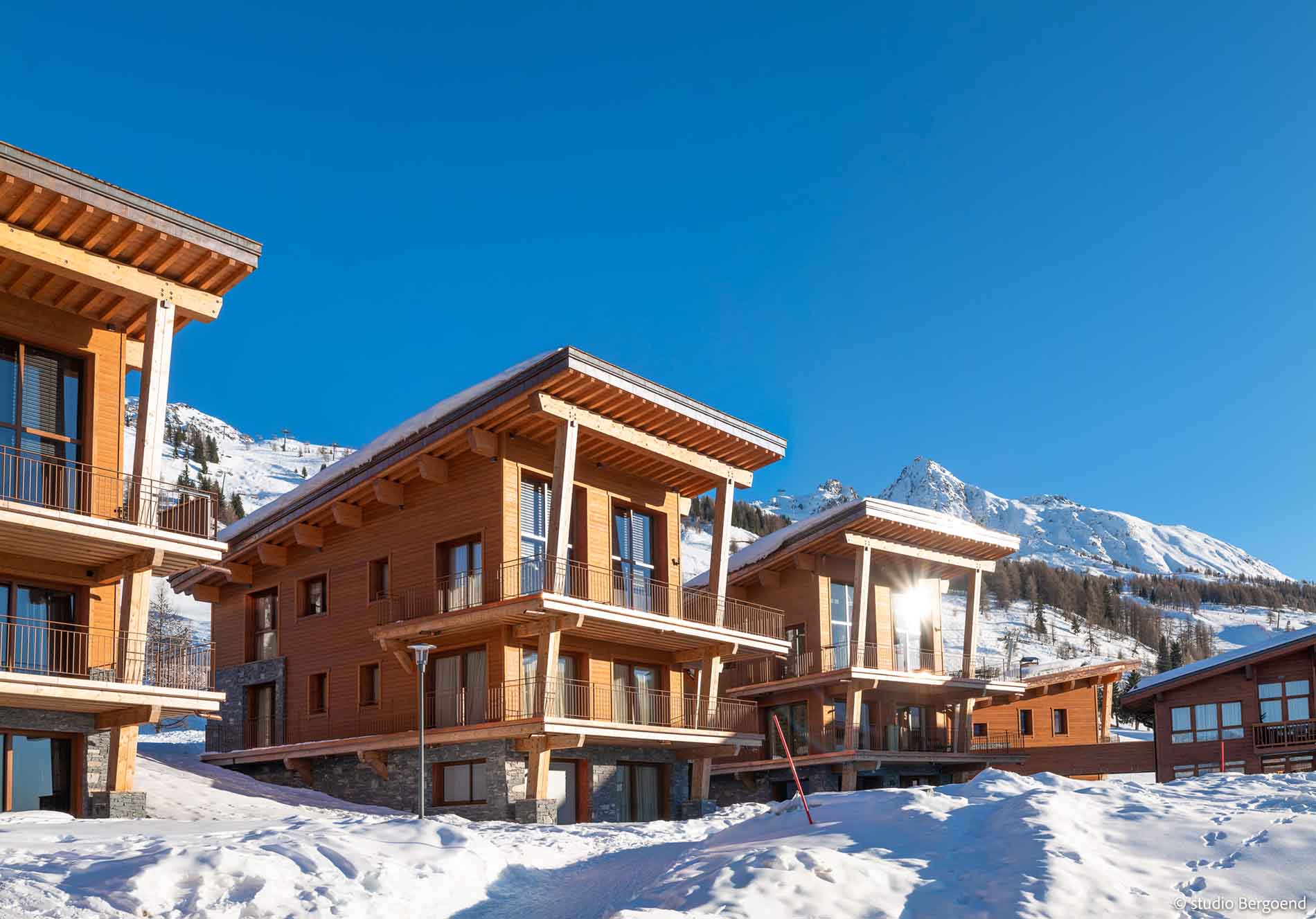 Fachada de chalé moderno em madeira em Les Arcs, com neve e montanhas ao fundo