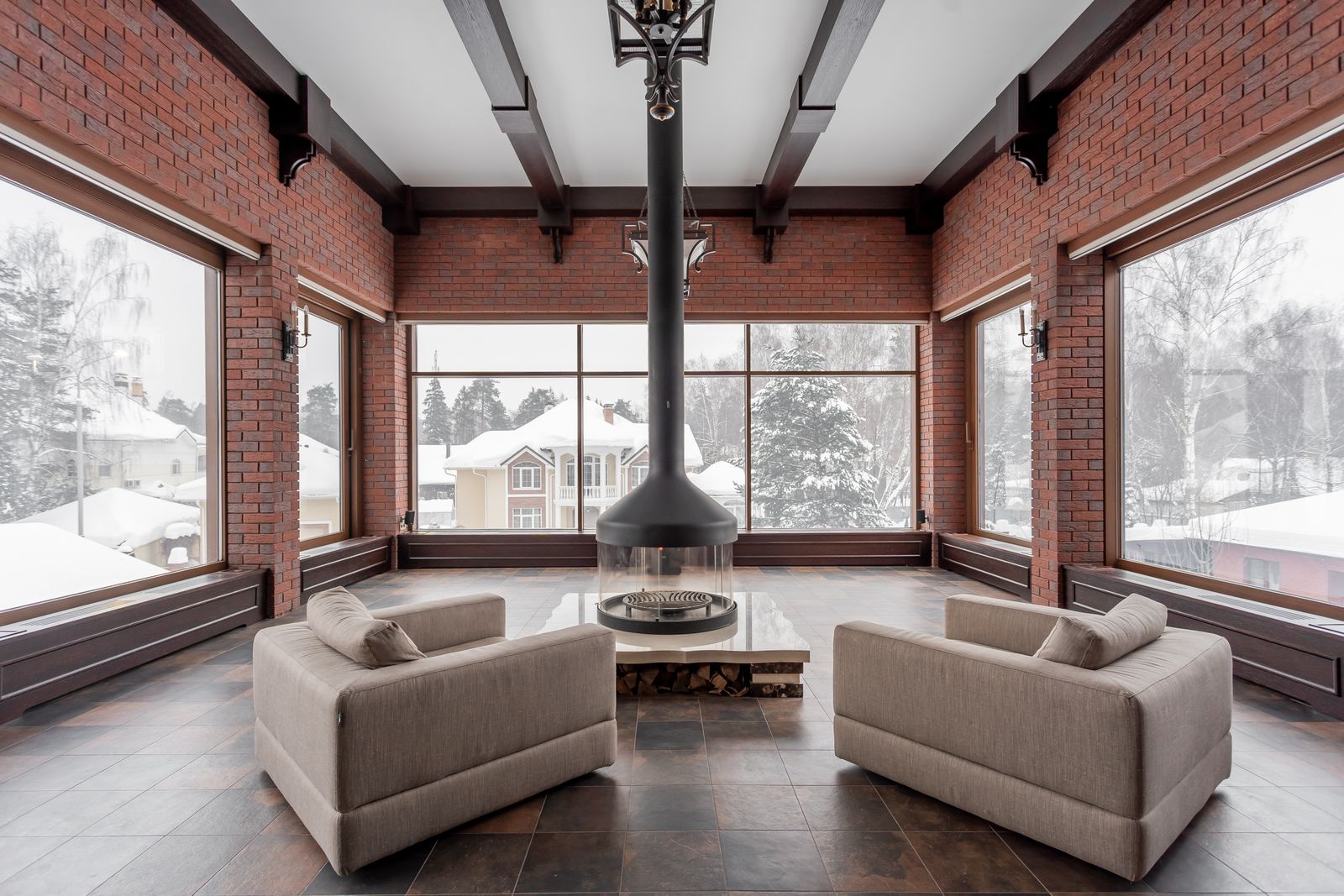 Lounge com lareira central e vista para casas cobertas de neve